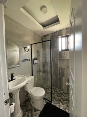 A bathroom with a pedestal sink, toilet, and glass-enclosed shower. - 3-bedroom house in wonderful Bonao with big pool (Bonao)