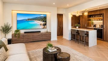 Uma sala de estar moderna com uma televisão de tela plana grande, um sofá e uma mesa de centro com objetos decorativos.