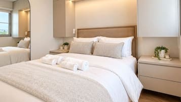 Quarto moderno com uma cama grande, mesa de cabeceira, espelho e armários embutidos.