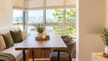 Cozinha moderna com mesa de madeira, banco embutido e vista para a cidade.