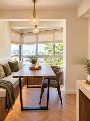 A modern kitchen with a wooden table, a built-in bench, and a view of the city. - Casa Rossa Lux 2-bedroom Apartment in Sea Point (Cape Town)