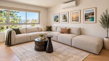 Uma sala de estar moderna com sofá em seção, mesa de centro e uma grande janela com vista para o exterior.