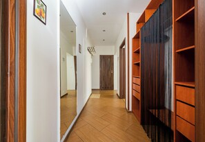 Ein Flur mit Holzboden, einem Spiegel links und einem Holzschrank rechts.