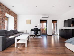 A modern living room with a sofa, coffee table, and TV. - Księży Młyn Loft Studio (Łódź)