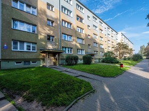 Un immeuble résidentiel à plusieurs étages, doté d’une façade plane, de fenêtres rectangulaires et d’un petit espace d’entrée avec une porte.