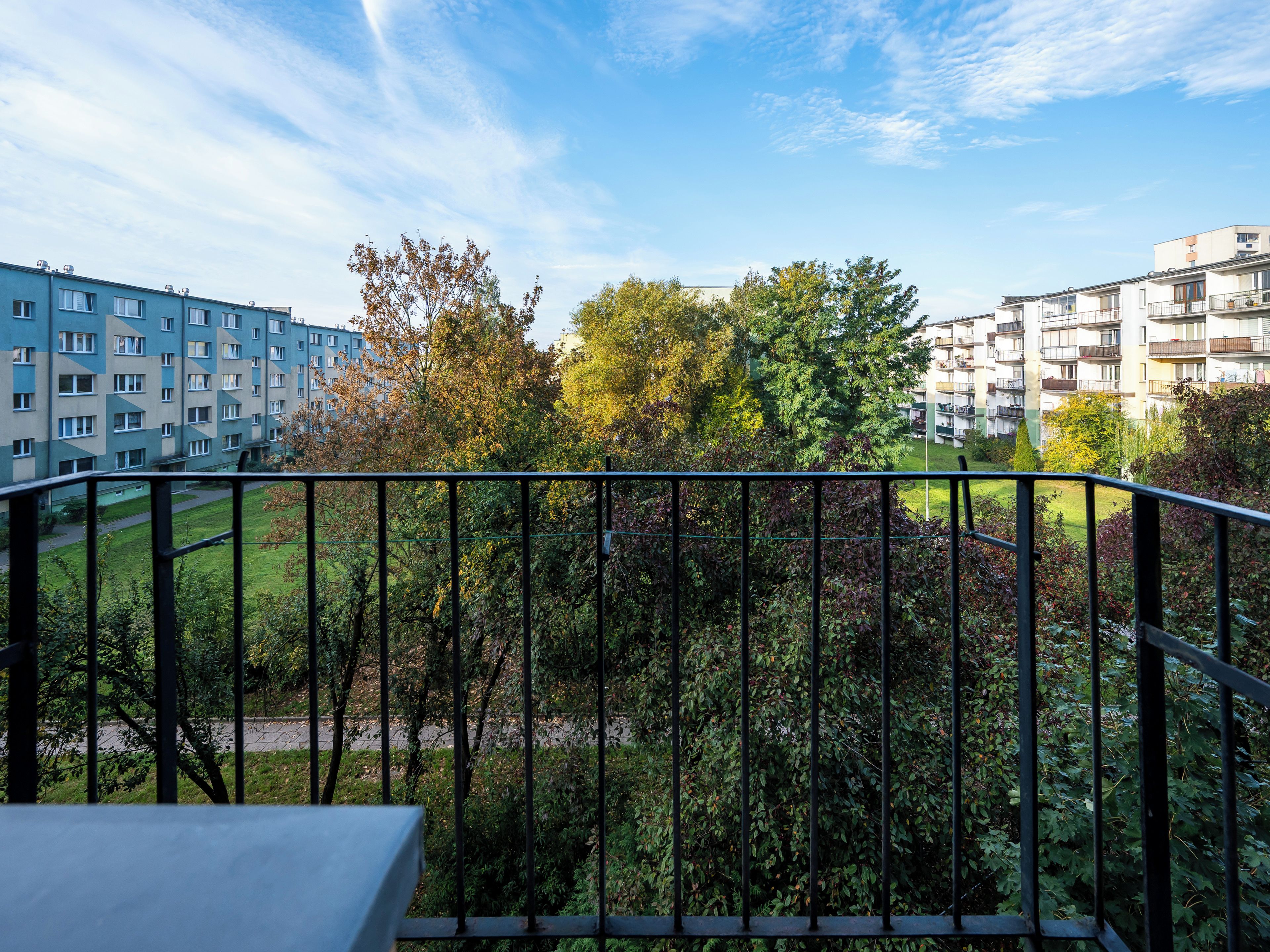 A balcony with a view of a residential area, including apartment buildings and a park.