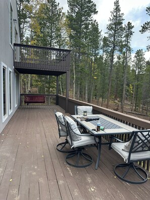 A wooden deck with a table and chairs, overlooking a forested area. - 4 Bedroom Private Mountain Home Near Golden, Boulder, Eldora Ski Resort (Golden)