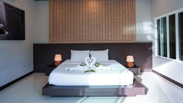 A modern hotel room with a large bed, two bedside lamps, a wall-mounted air conditioner, and a window with blinds.