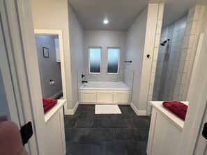 A bathroom with a bathtub, two windows, a shower, and dark tiled flooring. - Edmond 4BR Entertainment Retreat, Pool Table, Air Hockey, Ping Pong & Sleeps 10 (Edmond)