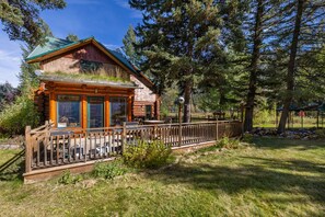 Eine Blockhütte mit einer Terrasse und Sitzgelegenheiten im Freien.