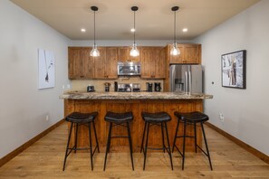 A kitchen with wooden cabinets, stainless steel appliances, and a granite countertop. - New! Private Hot Tub | Town Center | Sleeps 9 (Big Sky)