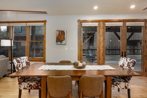 A dining area with a wooden table, cowhide upholstered chairs, and a painting on the wall. - New! Private Hot Tub | Town Center | Sleeps 9 (Big Sky)