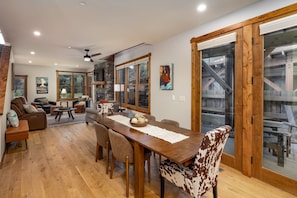 A spacious living area with a dining table, comfortable seating, and large windows. - New! Private Hot Tub | Town Center | Sleeps 9 (Big Sky)