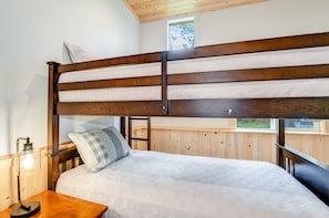 A bunk bed with a wooden frame and white bedding. There is a bedside table with a lamp and a bottle of hand sanitizer. - NEW | Minutes to Flathead Lake | Boat + Hike Lakeside | Creekside Log Home, Fire Pit, Sleeps 8 (Lakeside)
