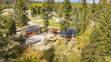 Un albergue con varias cabañas, una terraza techada y vistas del bosque circundante.
