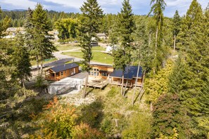 Un albergue con varias cabañas, una terraza techada y vistas del bosque circundante.