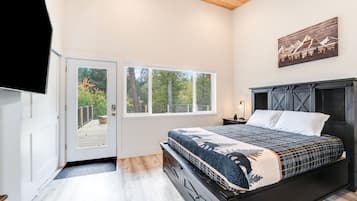 Une chambre avec un grand lit, un plafond en bois, une porte donnant sur un balcon et un tableau accroché au mur.