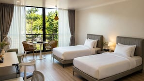 Habitación de hotel con dos camas, una mesa de comedor, sillas y un balcón con cortinas.