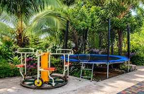 Un espace de jeux extérieur avec des balançoires et un trampoline.