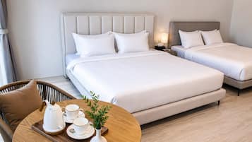 A hotel room with two beds, a round table with a tea set, and a wicker chair.