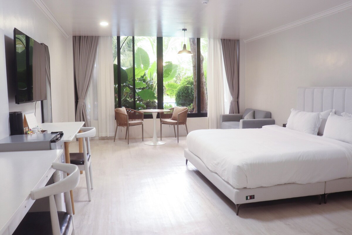 Une chambre d’hôtel moderne équipée d’un lit, d’un bureau, d’une chaise, d’une télévision et d’une fenêtre avec des rideaux.