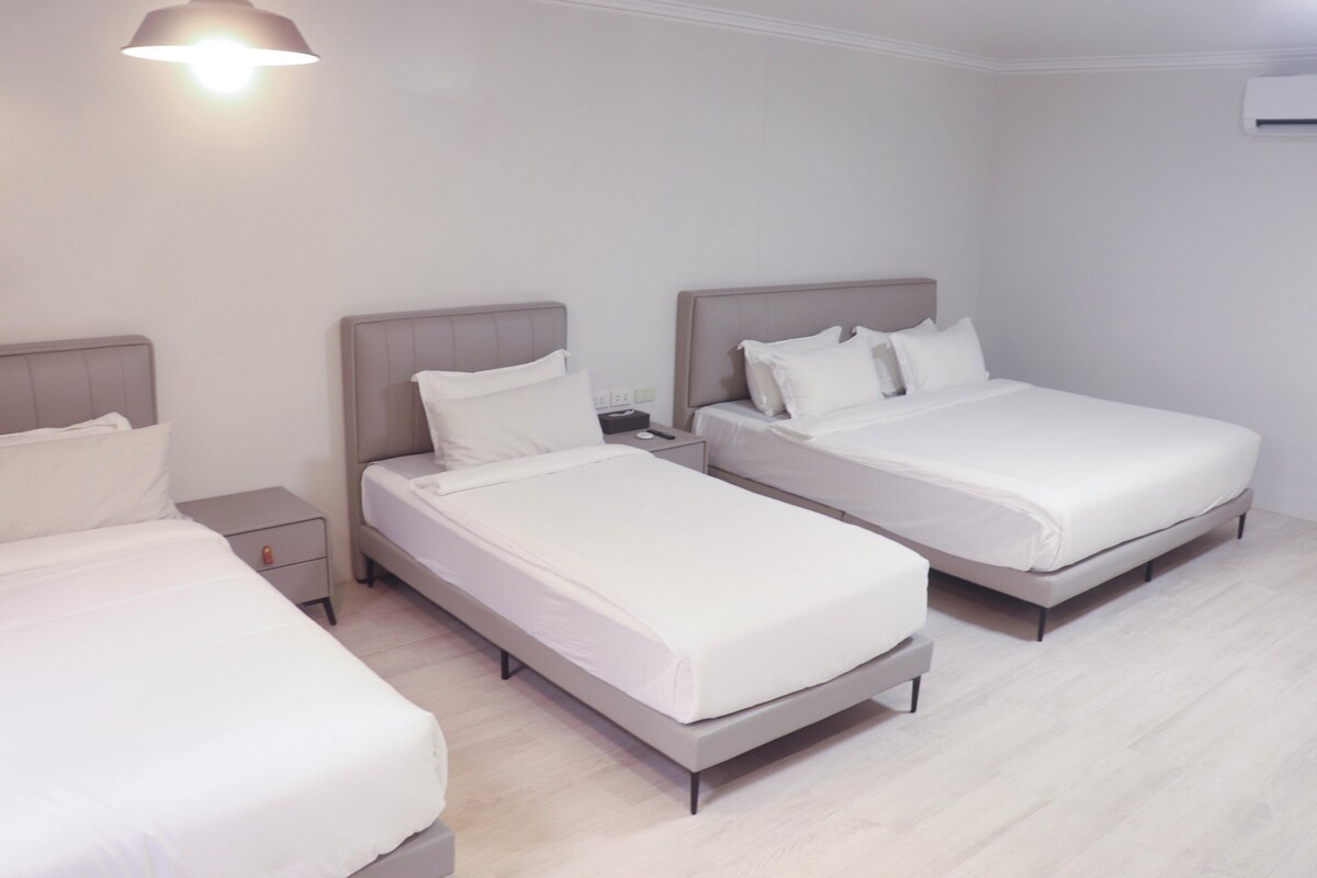 Une chambre d’hôtel avec deux lits simples, une table de chevet et un climatiseur fixé au mur.