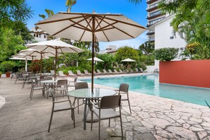 A poolside area with lounge chairs and umbrellas, a swimming pool, and surrounding greenery. - Casita Espléndida 2 Blocks from the Beach (Puerto Vallarta)