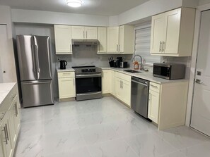 A modern kitchen with stainless steel appliances, white cabinetry, and a tiled floor. - 3BR-Upper level unit - Fleetwood-10 mins to HWY (Surrey)