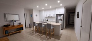 A modern kitchen with a central island, bar stools, and a built-in oven. - Rosebay Walk To The Foreshore (CAPEL SOUND)