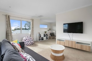 A modern living room with a sofa, a television, and a bookshelf. - Rosebay Walk To The Foreshore (CAPEL SOUND)