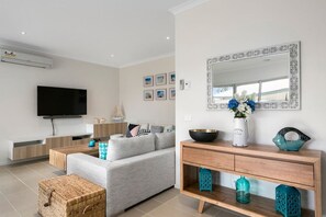A modern living room with a flat-screen TV, a sofa, a coffee table, and a wooden console with decorative items. - Rosebay Walk To The Foreshore (CAPEL SOUND)