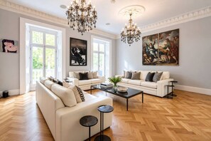 A spacious living room with two white sofas, a coffee table, and a chandelier. - Belgravia 4-bed Tennis Court Garden Access (London)