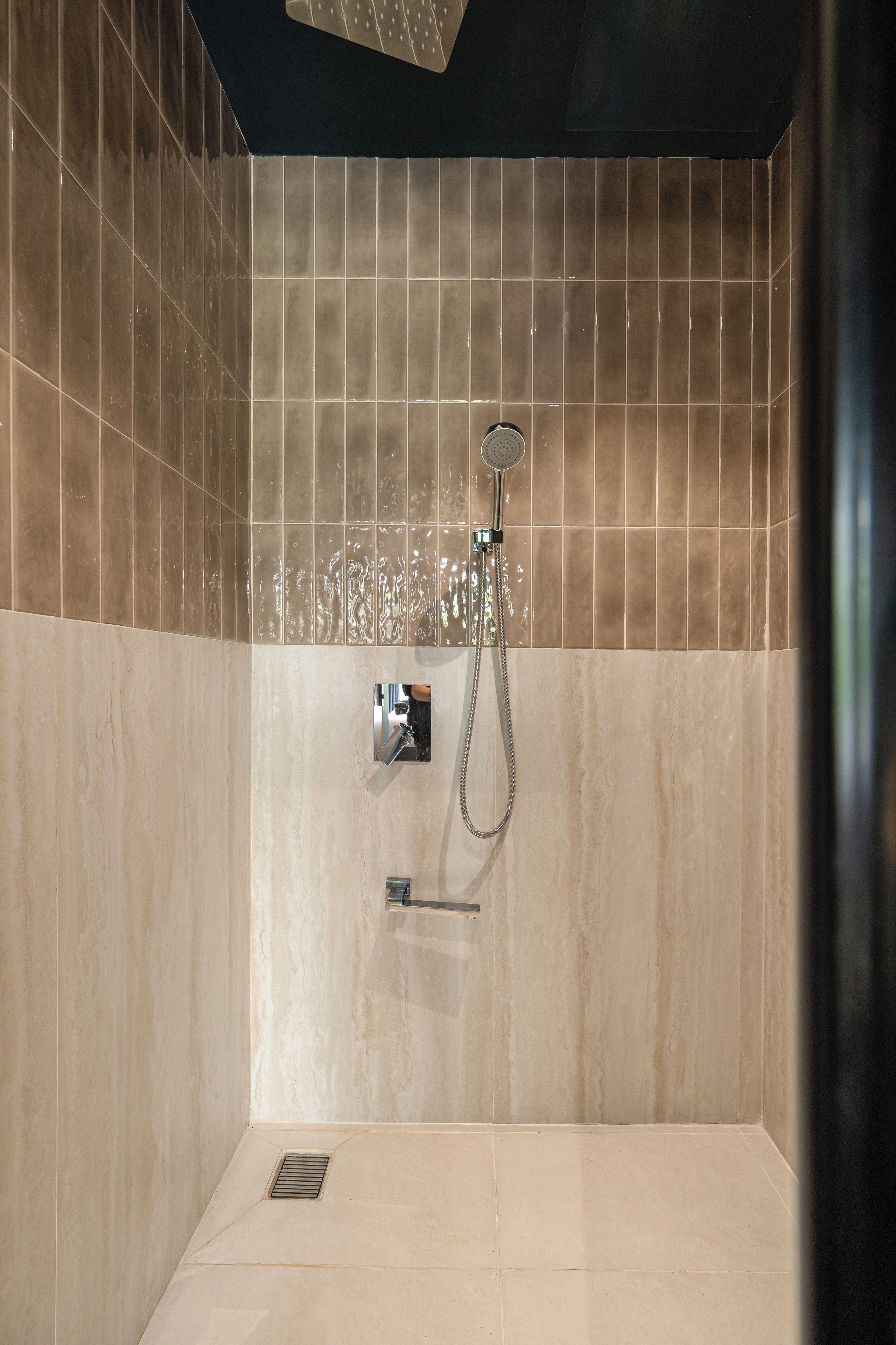 A modern bathroom with a shower, tiled walls, and a visible drain.