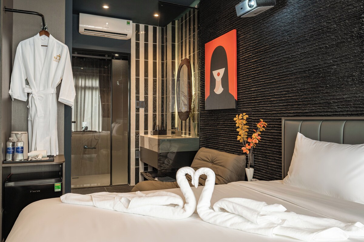 A hotel room with a bed, a robe, a mirror, a sink, and a wall with a textured design.