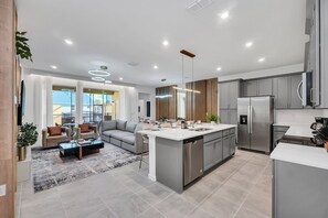 A modern kitchen with a central island, grey cabinetry, and stainless steel appliances. - Solara Resort 5BR Villa | Pool, Theme Room, Game Fun (Kissimmee)