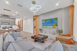 Ein modernes Wohnzimmer mit einer Couch, einem Couchtisch und einem Gemälde mit einer Strandansicht.