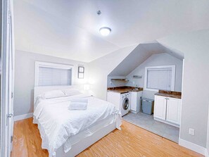 Ein Schlafzimmer mit einem Bett, einer Waschmaschine und einer Küchenzeile.
