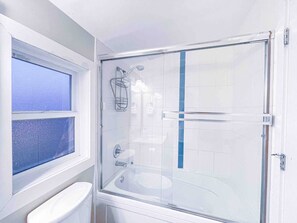 Ein Badezimmer mit Duschkabine aus Glas, Toilette und Waschbecken.
