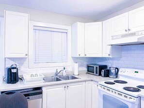 A modern kitchen with white cabinets, a built-in microwave, a stove, and a dishwasher. - V-2BR Laneway - 15 Mins To DownTown (Vancouver)