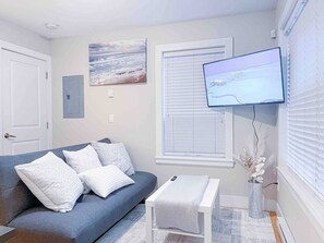 A living room with a sofa, a television, a small table, and a decorative vase. - V-2BR Laneway - 15 Mins To DownTown (Vancouver)