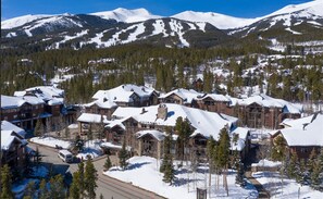 A snow-covered mountain town with lodge-style buildings, a clear sky, and a road leading through the area. - Grand Timber Lodge 1bd, Hot Tubs, Pools & Saunas (Breckenridge)