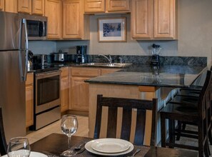 A kitchen with wooden cabinets, a stainless steel refrigerator, a microwave, a stove, and a sink. - Grand Timber Lodge 1bd, Hot Tubs, Pools & Saunas (Breckenridge)