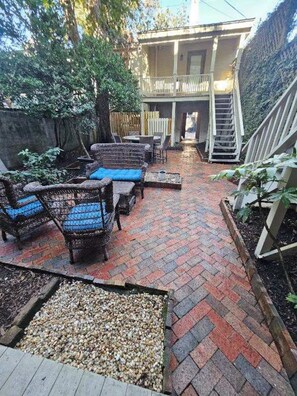 An outdoor patio area with wicker furniture and a brick pathway leading to a building. - Romantic Carriage House Near Forsyth Park, Parking (Savannah)