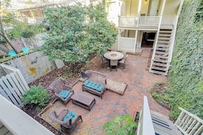 Un espace extérieur aménagé en terrasse, avec des meubles en osier, une table ronde et une clôture blanche.