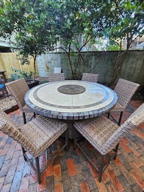 A round outdoor dining area with a mosaic table and wicker chairs. - Grand 1882 Victorian with 5BR, Steps to Forsyth Park (Savannah)