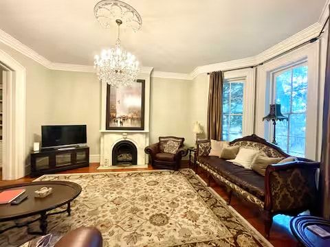 A living room with a fireplace, a sofa, a television, and a chandelier.