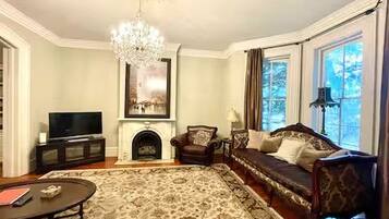 A living room with a fireplace, a sofa, a television, and a chandelier.