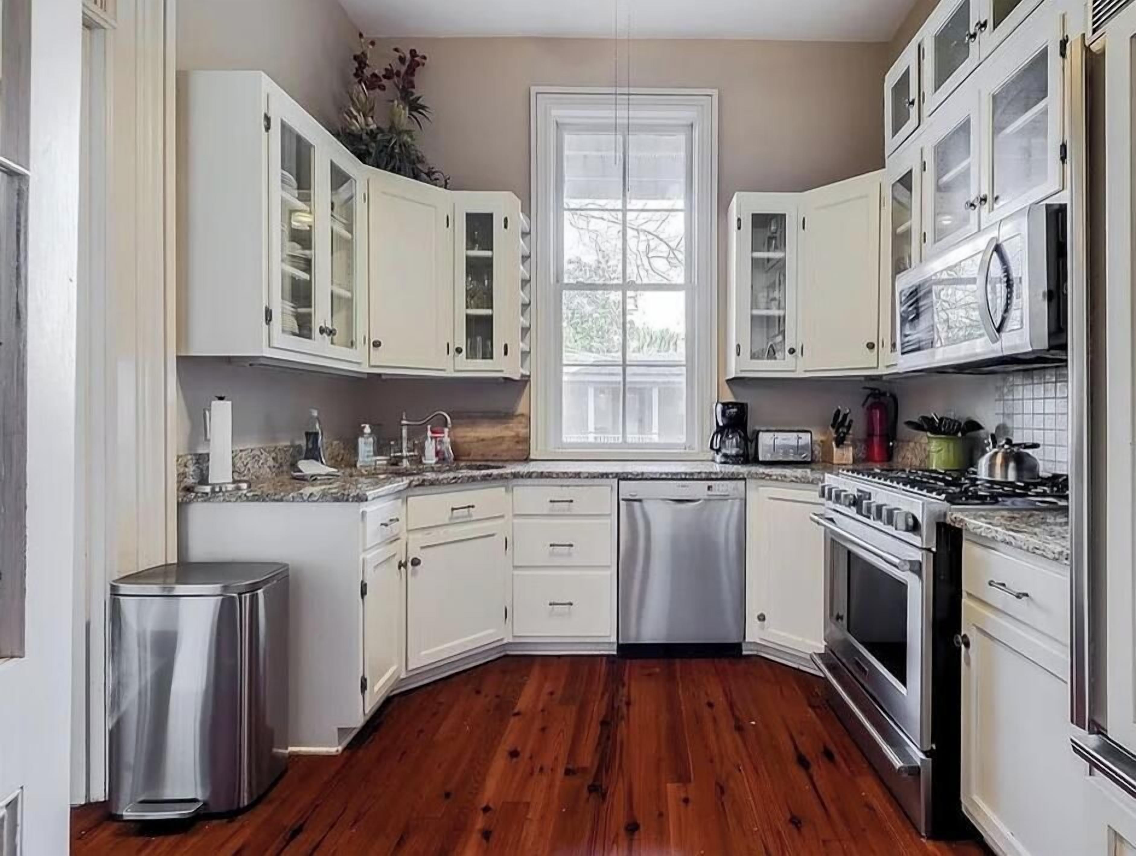 Una cocina con armarios blancos, lavavajillas, estufa y microondas.