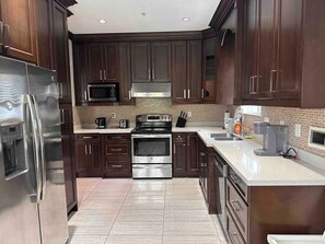 A modern kitchen with dark wood cabinets, stainless steel appliances, and a tiled backsplash. - Spacious 3bdrms in Vancouver for 8 people. NearPNE (Vancouver)
