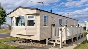 En campingvogn med veranda, skorsten og parabolantenne.